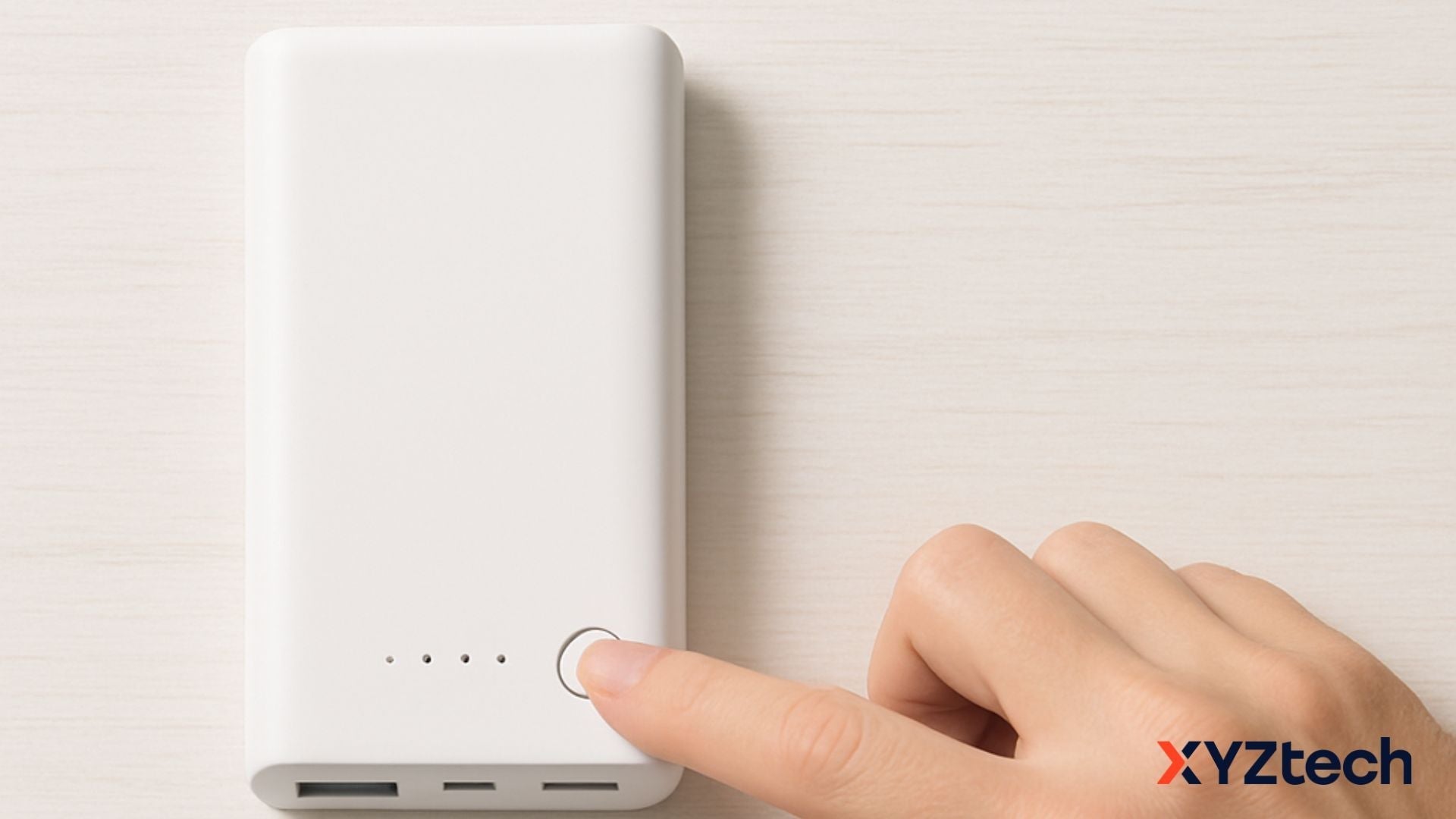 A finger pressing on a button of a white portable charger.