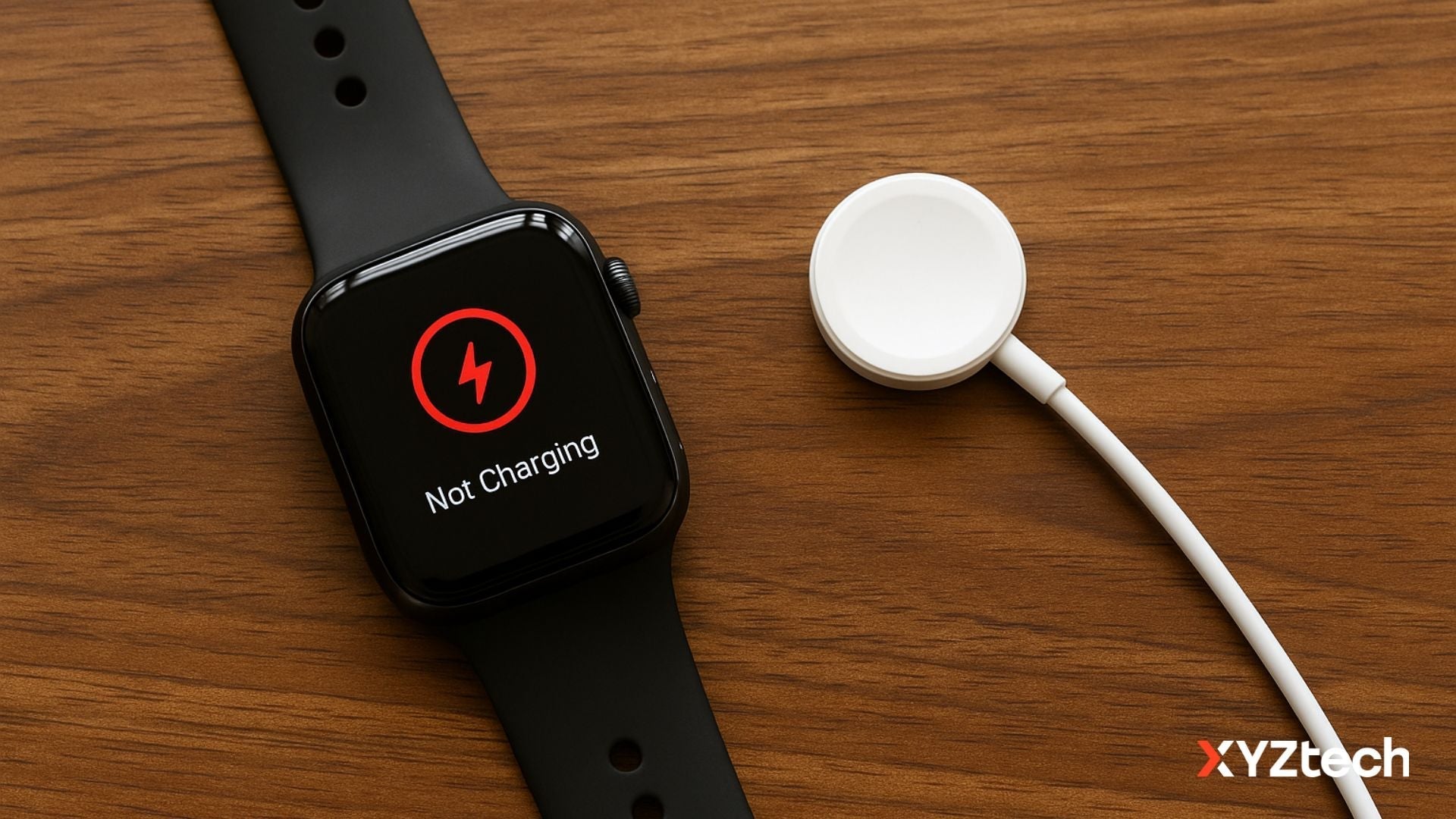 A black Apple Watch with a “Not Charging” symbol displayed on its screen lies on a wooden desk next to a disconnected white magnetic charging puck.