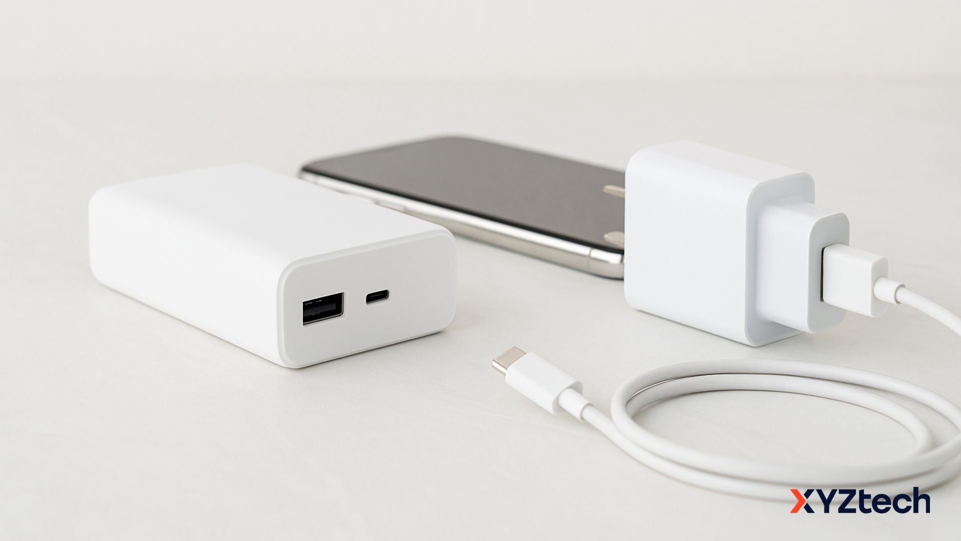 A smartphone, a charger, and a power bank on a table.